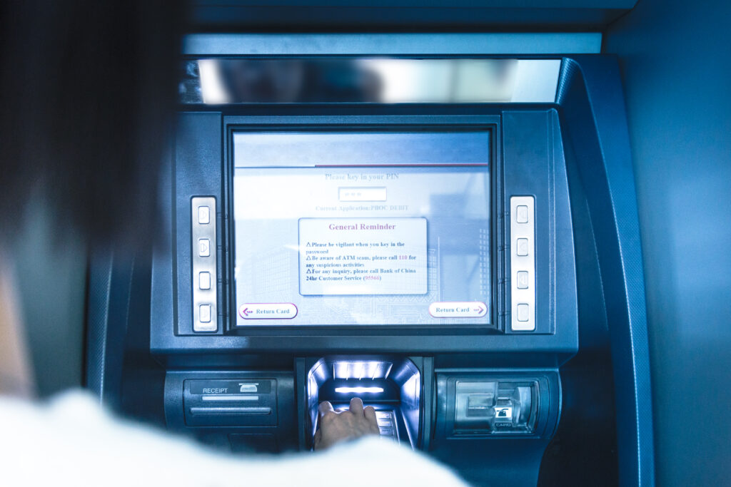 A woman is using an atm machine.